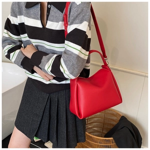 Gros plan d'un sac à main rouge vif en cuir avec texture litchi porté par un modèle
