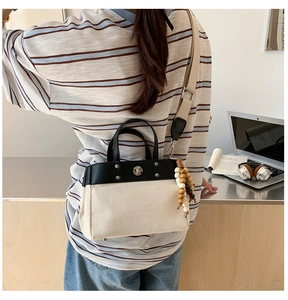 Detalle de bolso tote de lona con adornos de cuero negro y correa ancha ajustable