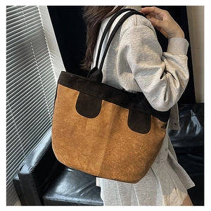 Side view of large contrast tote bag in brown suede and black faux leather on model
