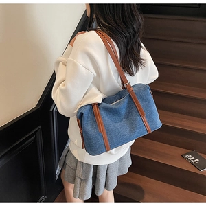 Borsa tote in denim blu con finiture in pelle marrone indossata da modella stile casual
