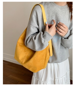 Detail of yellow faux suede hobo bag shown as a crossbody on model in casual setting
