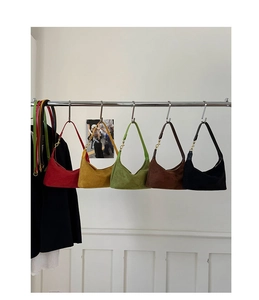 Close-up of semi-circle suede hobo bags in multiple colors hanging on a metal rack