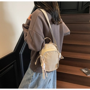 Detail of beige nylon square bag with natural wrinkled texture and decorative knot charm