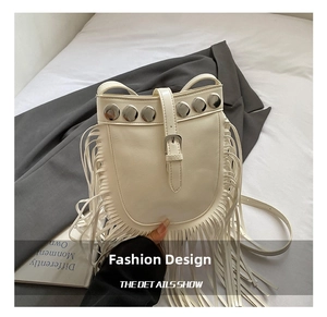 Detailed view of white fringed crossbody bag with silver studs on a stylish setting