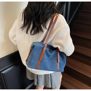 Dettaglio della borsa a cuscino in denim blu con cinturini in pelle e zip in metallo