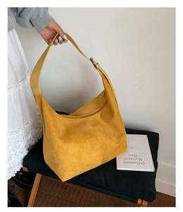 Detail of yellow suede hobo bag featuring wide strap and adjustable metal buckle