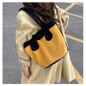 Outdoor shot of a yellow corduroy tote bag with black accents and wide shoulder strap