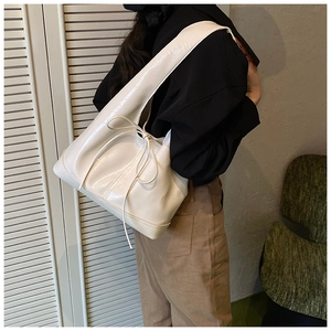 Detail view of glossy cream faux leather tote bag with elegant decorative ribbon bow