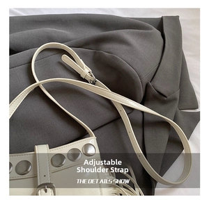 Close-up of adjustable shoulder strap with silver buckle on beige studded bucket bag