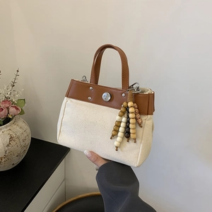 Bolso tote de lona con ribete de cuero marrón y colgante de borla con cuentas de madera