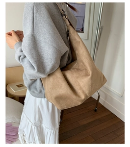 Close-up of light brown suede tote bag featuring adjustable wide strap and soft matte texture