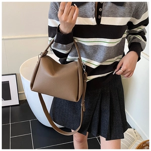 Detailed view of a brown pebbled leather crossbody bag with adjustable strap and top handle