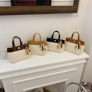 Bolsos tote de lona con adornos de cuero en cuatro colores sobre superficie blanca mínima