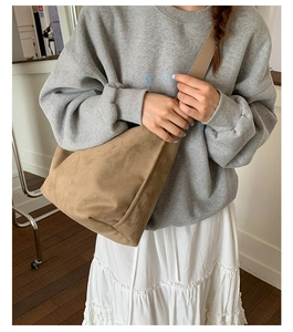 Detail of a large brown suede crescent tote bag showing slouchy texture on a model