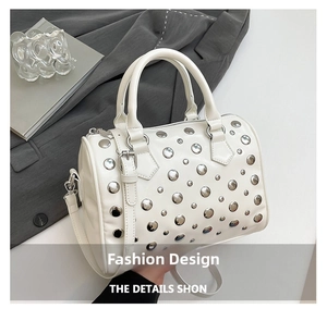 Detail of white Boston bag featuring silver rivet studs and detachable leather strap