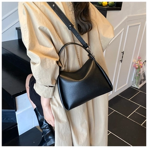 Détail d'un sac seau en cuir noir grainé avec poignée et bandoulière réglable