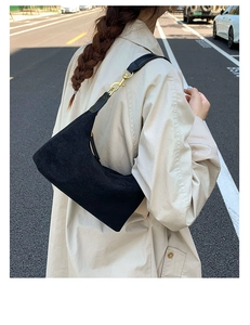Close-up of black suede hobo bag with vintage gold metal hardware on outdoor background