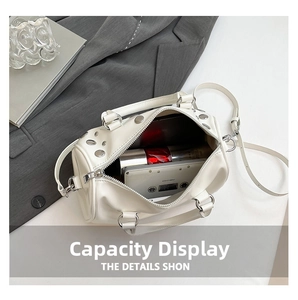 Spacious interior of white studded boston bag showing phone and makeup storage