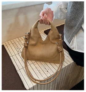 Close-up of brown suede hobo bag featuring unique knot detail on the shoulder strap