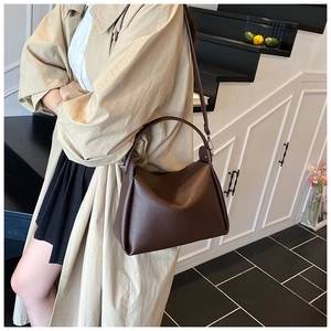 Detail of dark brown pebble leather handbag showing texture and side folding structure