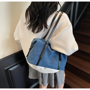Dettaglio borsa a tracolla in denim blu con cinturino in pelle nera e fibbia regolabile