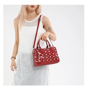 Detail of red patent leather Boston bag featuring silver studs and adjustable strap