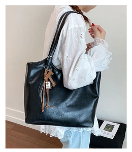 Side view of large black leather tote bag with brown horse charm for women's daily commute