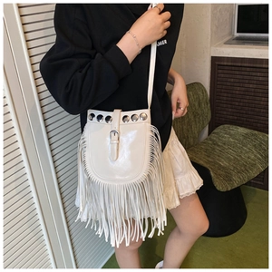 Bohemian white fringe saddle bag with metal studs worn by model in a lifestyle setting