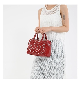 Detail of red patent leather Boston bag with silver rivets and dual handles