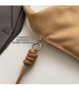 Close-up of brown suede bag featuring silver metal rings and premium leather knot detail