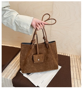 Detail of matte brown tote bag with decorative knot handle and small matching coin purse