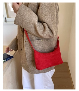 Detail of red suede crossbody tote bag styled with a beige textured blazer outfit