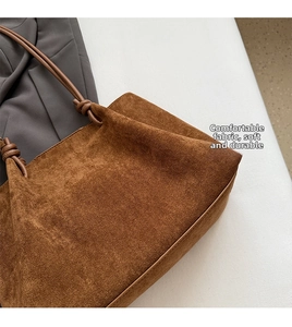Detail of brown matte suede shoulder bag with visible stitching and knotted strap design