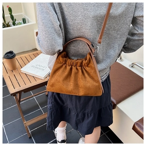 Détail d'un sac nuage en daim marron montrant la texture douce et les poignées