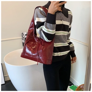 Detailed view of the dark red glossy patent leather tote with chic bow decoration