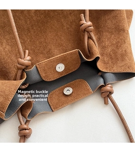Macro shot of magnetic buckle design and matte leather texture on brown tote bag