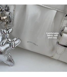 Detail of white glossy shoulder bag featuring silver metal hardware and star charms