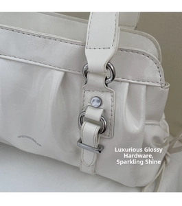 Close-up of white glossy shoulder bag with silver hardware and pleated leather texture