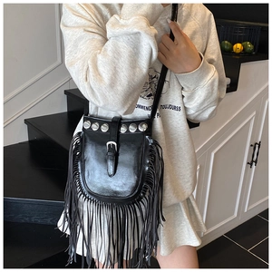 Detail of black leather crossbody bag with long fringes and silver stud decorations