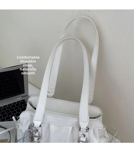 Detail of white PU shoulder bag featuring pleated edges and elegant silver metal buckles