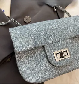 Detail of light blue denim quilted bag with silver metal turn-lock and chain strap
