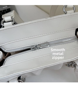 Detail of silver metal zipper and smooth leather texture on white shoulder bag