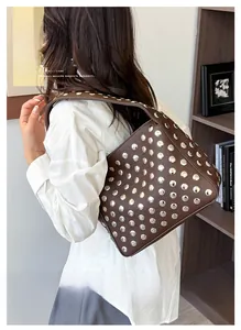 Brown vintage faux leather shoulder bag with silver metal rivets shown on a model's arm