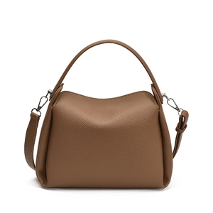 Détail du cuir grainé caramel et des finitions argentées sur un sac seau structuré