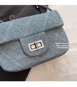 Close-up of blue denim quilted bag featuring silver hardware lock and metal chain strap