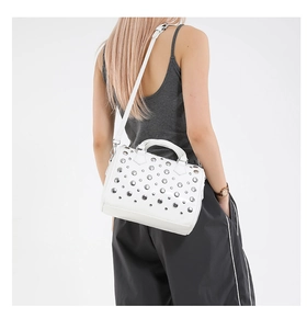 Detail view of white leather Boston bag featuring silver studs and adjustable shoulder strap