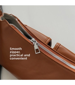 Detail of smooth silver metal zipper and precise stitching on caramel leather bag