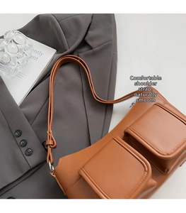 Detailed view of brown minimalist shoulder bag with dual front flap pockets and silver hardware