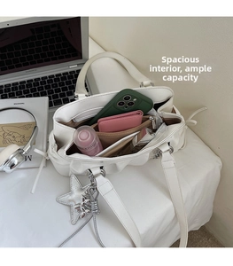 Interior view showing the large capacity and pockets of the white pleated shoulder bag