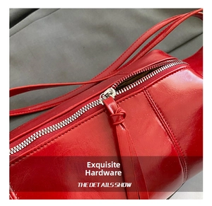 Detail of red patent leather shoulder bag featuring silver metal zipper and stitching